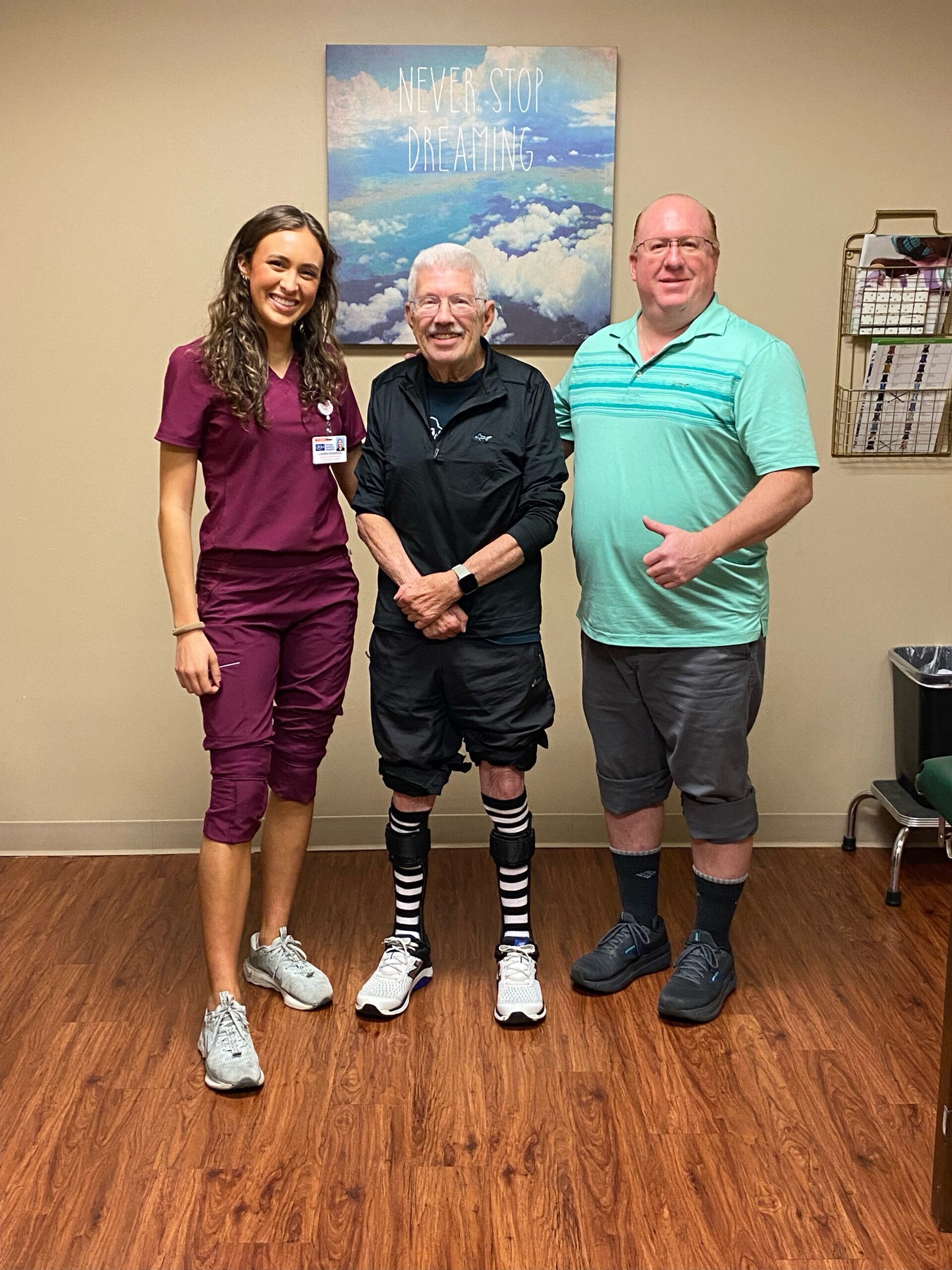 man wearing AFO braces, standing between a woman and man